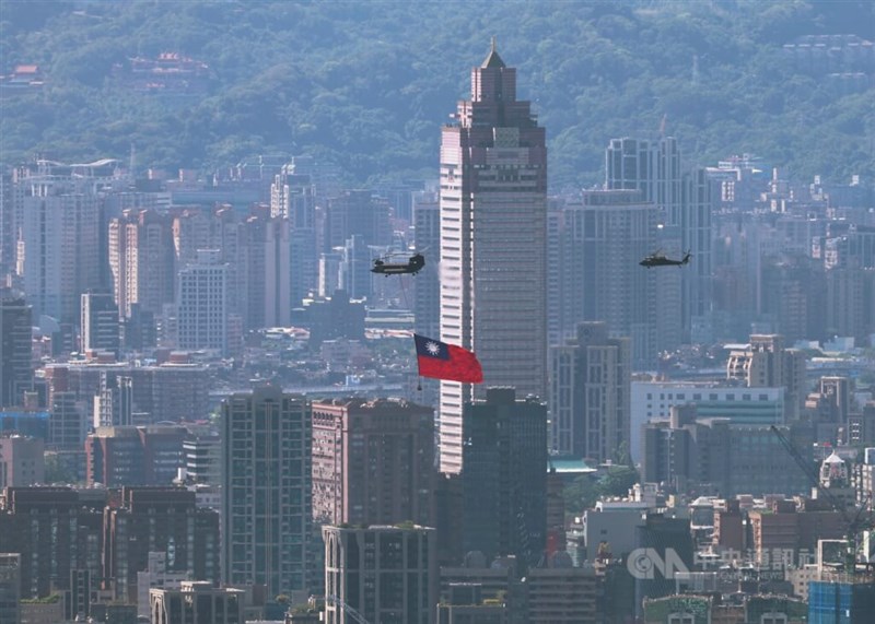 台北市の市街地を飛行する巨大な国旗をつるした国軍のヘリコプター「アパッチ」＝2025年10月10日、中央社記者趙世勲撮影