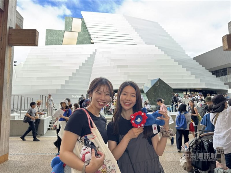 「テックワールド館」を背に記念写真に納まる女性たち＝10月13日、大阪市