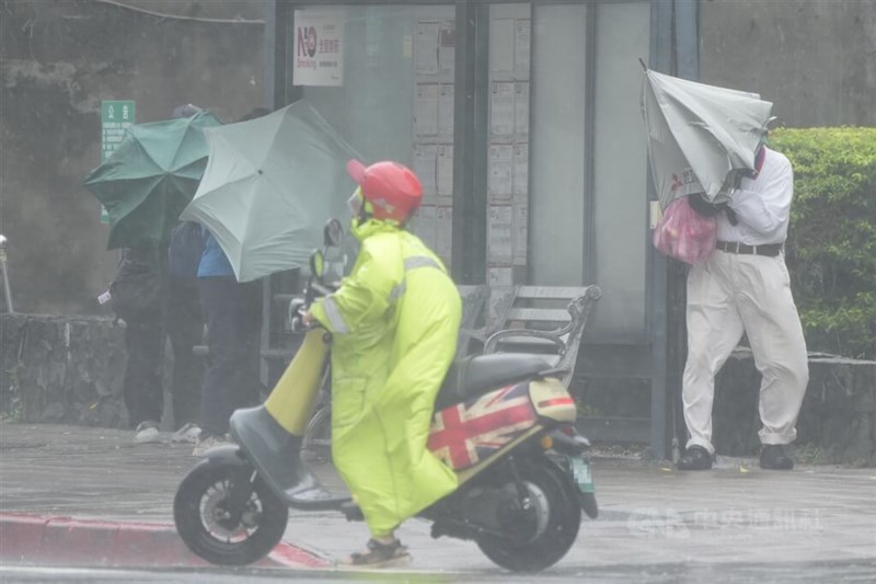 大雨の中、強風にあおられてバス停のそばに避難する人々＝2025年10月20日、台北市北投区で中央社記者徐肇昌撮影