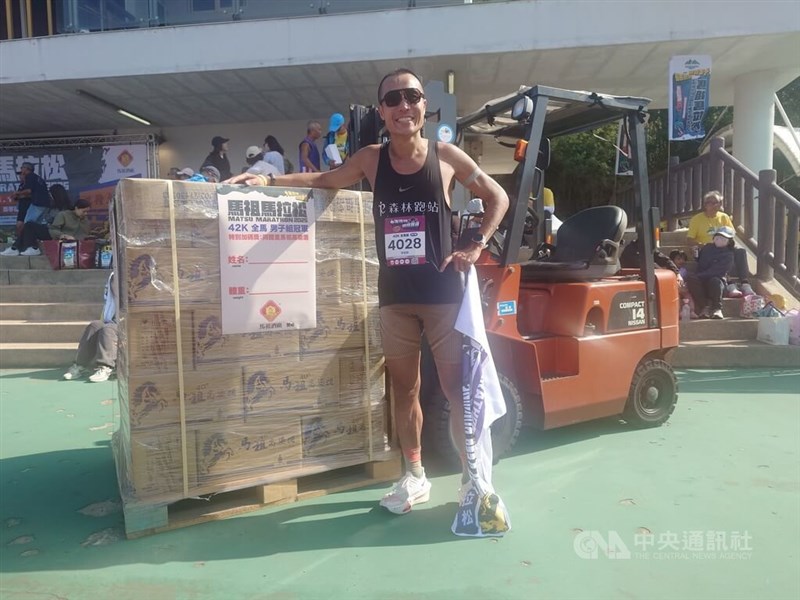 馬祖マラソン男子フルの部で優勝した李智群さんと自身の戦利品、重さ70キロに達する高粱酒＝2025年11月1日、中央社記者潘欣彤撮影