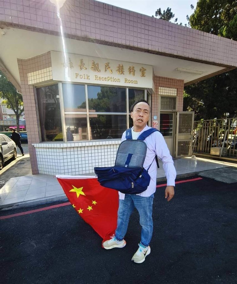 中華人民共和国国旗がデザインされた旗を手に「台湾統一」などと書かれたビラをまいた中国籍の男＝11月5日、金門県（読者提供）