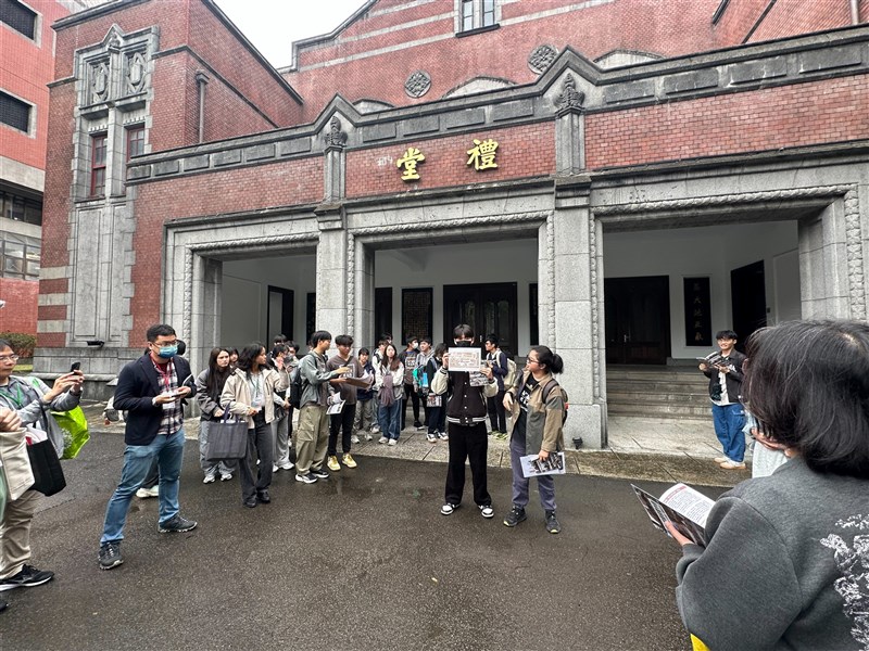 旧講堂(現礼堂)の前で建物の開設をする学生ら