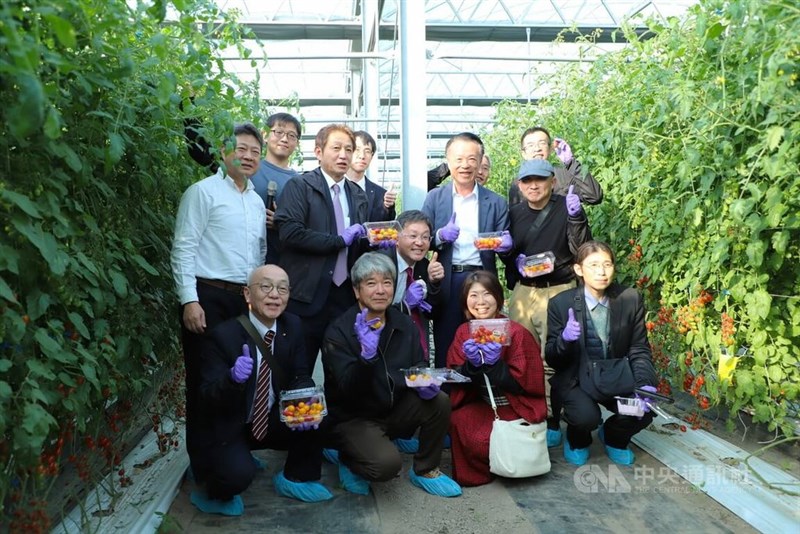 トマト農園で山口県からの視察団メンバーを出迎えた嘉義県の翁章梁県長（2列目右から2人目）＝1月14日、嘉義県