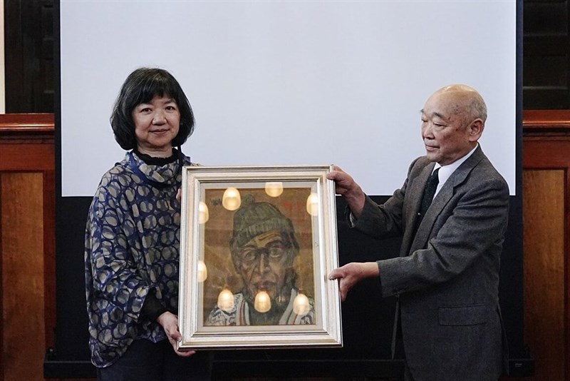 台南国家美術館準備処は25日、日本・山口県で開かれた台日交流シンポジウムで日本の画家・佐伯信夫の門下生である藤崎恒頼さん（右）から、佐伯信夫の作品「自画像」の寄贈を受けた。文化部の李静慧政務次長（左）が代表して受け取った＝同部提供