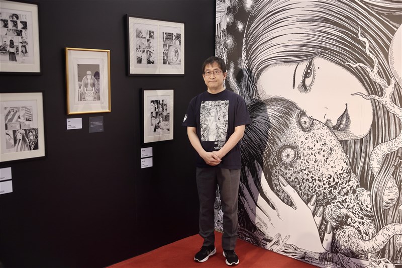 展示作品を背景に記念撮影に応じる漫画家の伊藤潤二さん＝2026年6月18日、中央社記者王飛華撮影