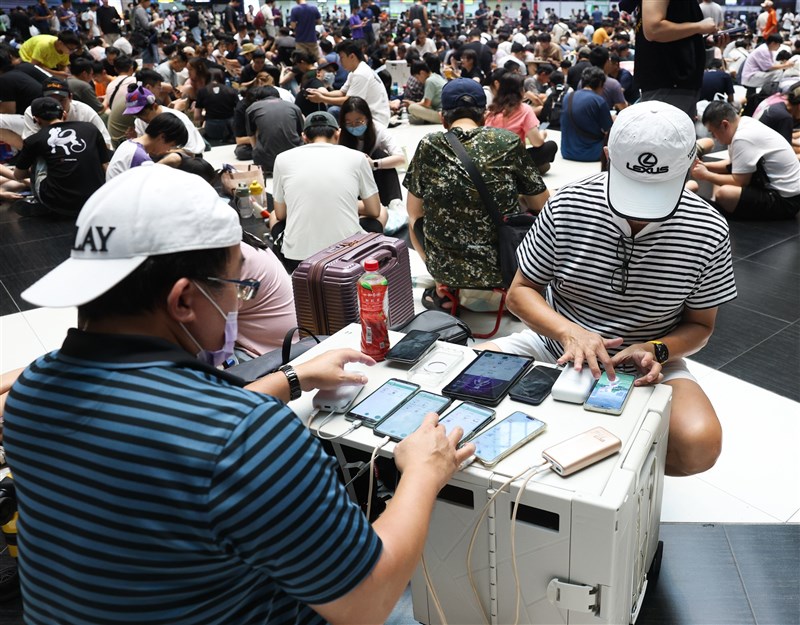 台北駅で複数のスマートフォンを操作して「ポケモンGO」をプレーする「トレーナー」ら＝2026年7月11日、中央社記者謝佳璋撮影
