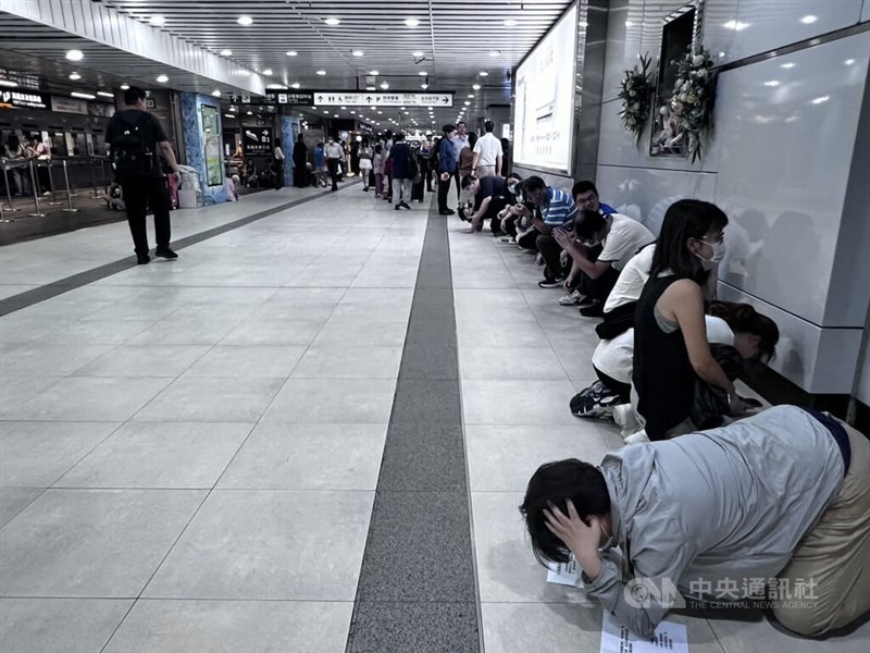 台北駅の地下1階通路で演習終了まで待機した利用者。係員の指示の下、避難時の防御姿勢を取る訓練も実施された＝8月13日、台北市