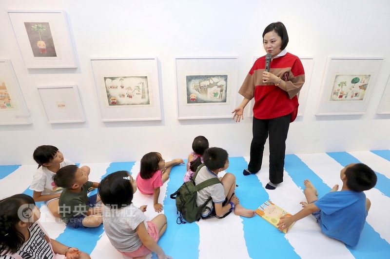 插畫家李瑾倫(立者)14日在台北出席「我和李瑾倫的攝影展+子兒吐吐25原作展」開幕,並親自介紹展出的17幅圖畫書「子兒,吐吐」原作,小朋友們專注聆聽。中央社記者吳翊寧攝 107年7月14日