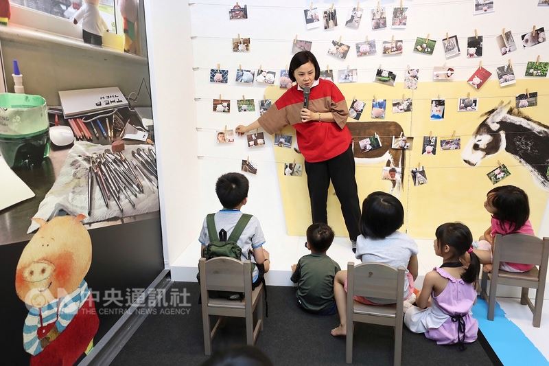 曾以圖畫書「子兒,吐吐」榮獲信誼幼兒文學獎第6屆首獎的插畫家李瑾倫(後)14日在台北舉辦以書中主角胖臉兒為主題的攝影展暨子兒吐吐25原作展,親自向小朋友介紹攝影作品。中央社記者吳翊寧攝 107年7月14日