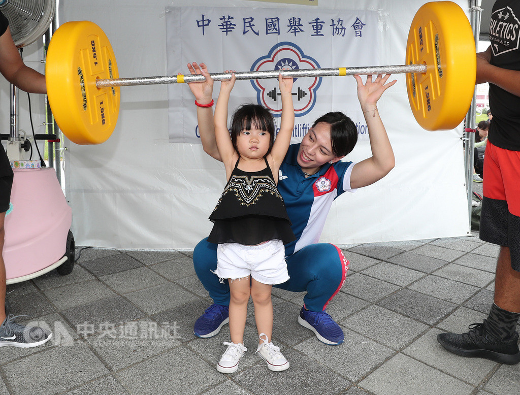 中華奧會22日在台北花博公園花海廣場舉辦首屆奧林匹克親子運動嘉年華,亞運舉重女子58公斤量級金牌的郭婞淳(後)陪小朋友體驗舉重樂趣。中央社記者張新偉攝 107年9月22日