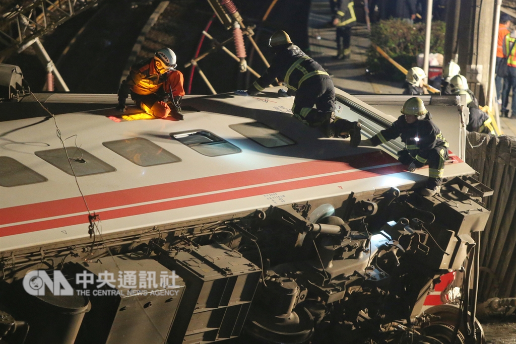 台鐵6432次普悠瑪列車21日下午在宜蘭發生出軌事故,造成重大傷亡,搜救人員晚間仍未停止救援行動,爬上翻覆車廂從車窗探視車內狀況。 中央社記者徐肇昌攝 107年10月21日