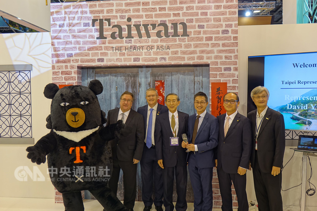 全球第二大旅展倫敦WTM旅展5日揭幕,駐英代表林永樂(中)和台英國會小組副主席羅森代(左3)與吉祥物喔熊合影。中央社記者戴雅真倫敦攝 107年11月6日