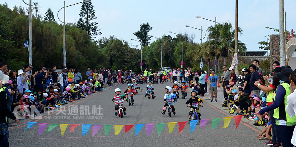 澎湖主委盃直排輪暨滑步車公路賽11日在馬公市觀音亭旁的西瀛勝境附近路段舉行,小朋友全副裝備、頭戴護盔,腳踩滑步車奔馳競速,大人們在道路旁加油。中央社 107年11月11日