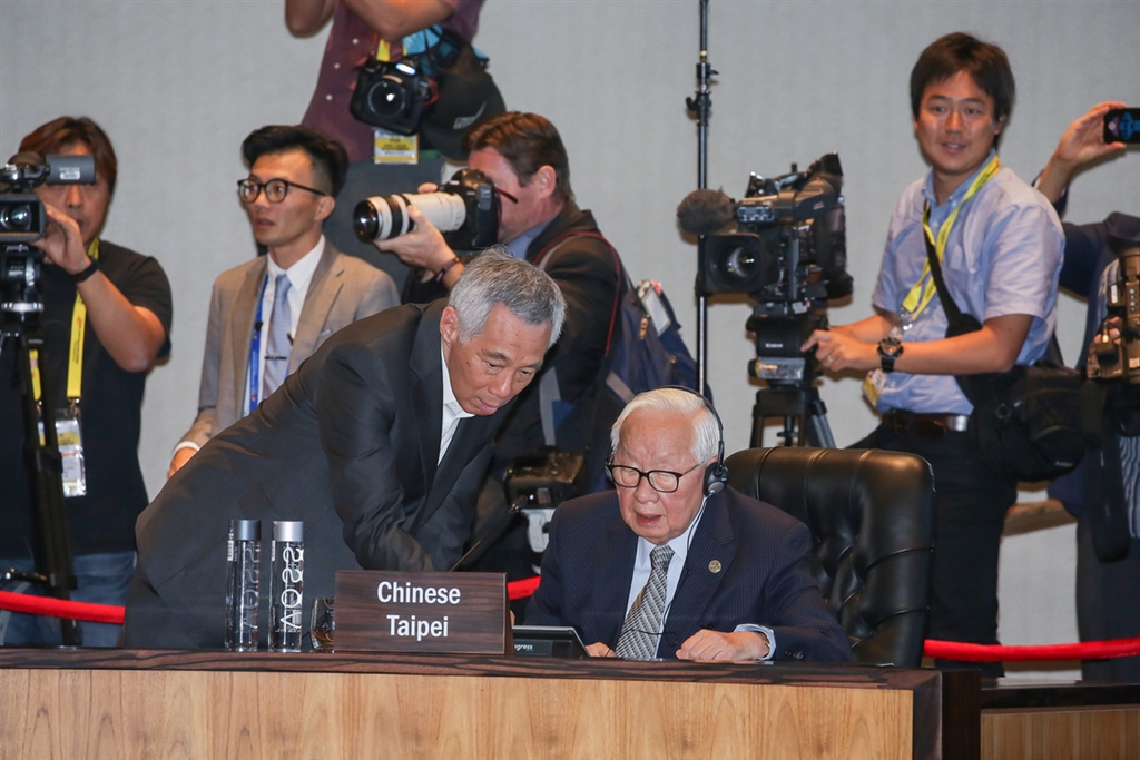 亞太經合會(APEC)領袖閉門會議18日舉行,APEC領袖代表張忠謀在會場裡坐在新加坡總理李顯龍、泰國總理帕拉育(Prayut Chan-O-Cha)中間,圖為李顯龍協助張忠謀操作現場設備。(中華台北代表團提供)中央社記者廖禹揚傳真 107年11月18日