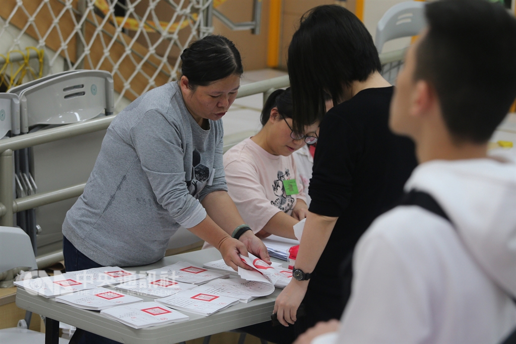 107年地方公職人員選舉及全國性公民投票案第7案至第16案24日登場,選務人員發放10張公投票給投票民眾。中央社記者徐肇昌攝 107年11月24日
