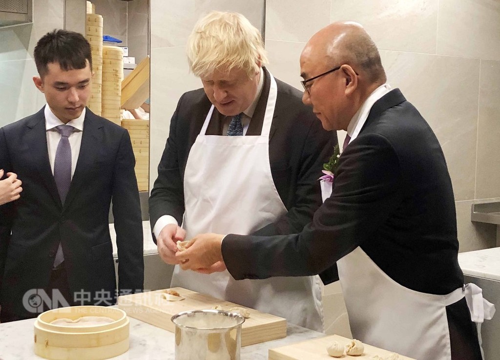 鼎泰豐進軍英國倫敦開設歐洲首店,5日舉行開幕儀式,前英國外相強生(中)在鼎泰豐董事長楊紀華(右)指導下,體驗製作鼎泰豐招牌的18褶小籠包。中央社記者戴雅真倫敦攝 107年12月6日
