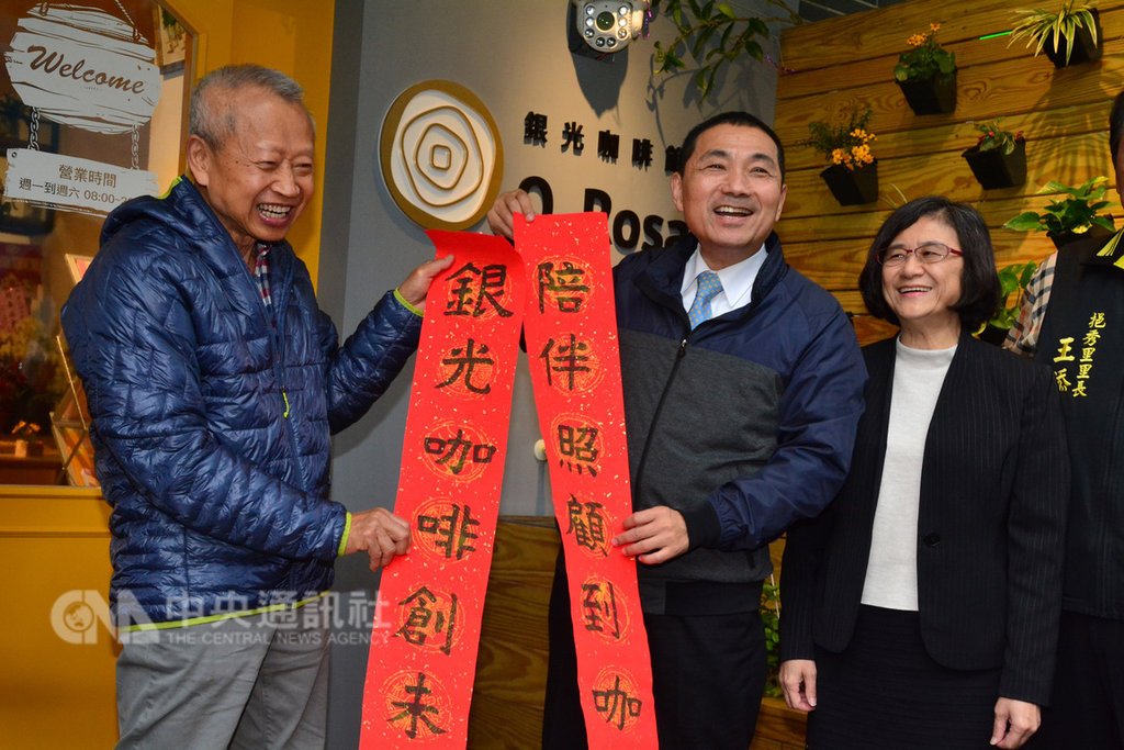 新北市首家長照創新服務據點「銀光咖啡館」17日開幕,長者洪文珍(左)揮毫寫下對聯「陪伴照顧到咖手,銀光咖啡創未來」,並與市長侯友宜(中)等人一同為咖啡館揭幕。中央社記者黃旭昇新北市攝 108年1月17日