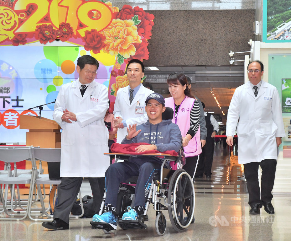 傘兵秦良丰107年5月執行反空降操演時自高空墜地受重傷,奇蹟存活。歷經10個月的治療,5日上午將從台北三總轉院至高雄三總,方便後續復健,同時也晉升為下士。圖為秦良丰(前)坐輪椅離開台北三總時,向大家揮手致意。中央社記者王飛華攝 108年3月5日