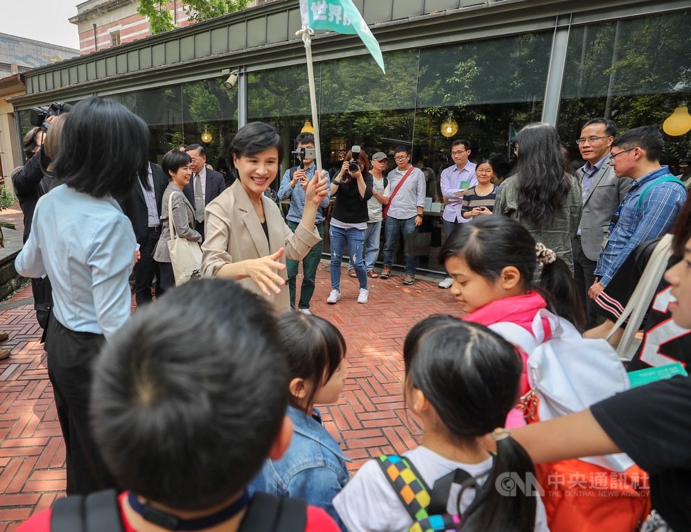 2019世界閱讀日啟動記者會17日在台北舉行,現場並安排走讀活動,由導覽員解說園區樟腦工廠的故事,文化部長鄭麗君(舉旗者)邀請路過學童一起參與。中央社記者裴禛攝 108年4月17日