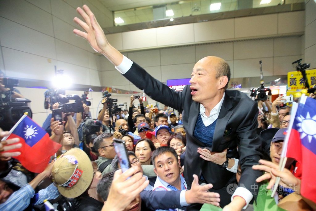 高雄市長韓國瑜夫婦18日清晨搭機返抵國門,吸引許多支持民眾到機場接機,現場2名男子更抱著韓國瑜的大腿將他高高舉起,而韓國瑜也不斷揮手向支持群眾打招呼。中央社記者吳睿騏桃園機場攝 108年4月18日