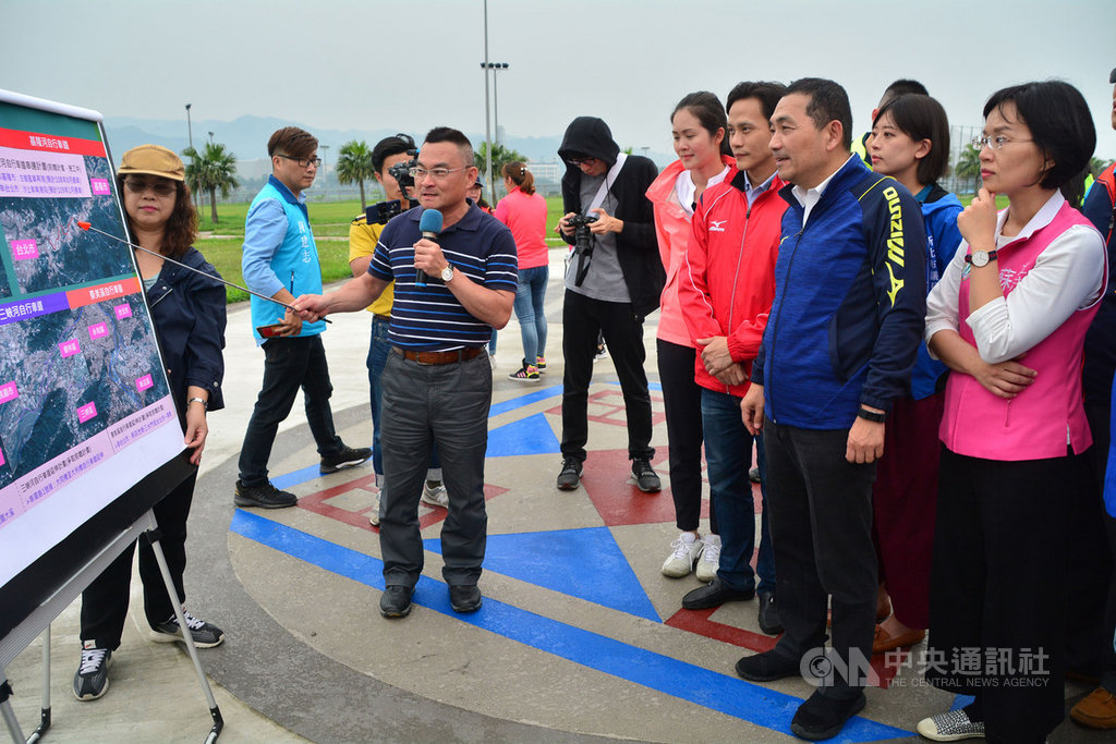 新北市長侯友宜(前右2)19日在大漢溪畔聽取市府水利局高灘地工程管理處長謝俊隆(前左持麥克風者)簡報,說明串連新北市與桃園市的大漢溪自行車道興建工程進度。中央社記者黃旭昇新北攝 108年4月19日
