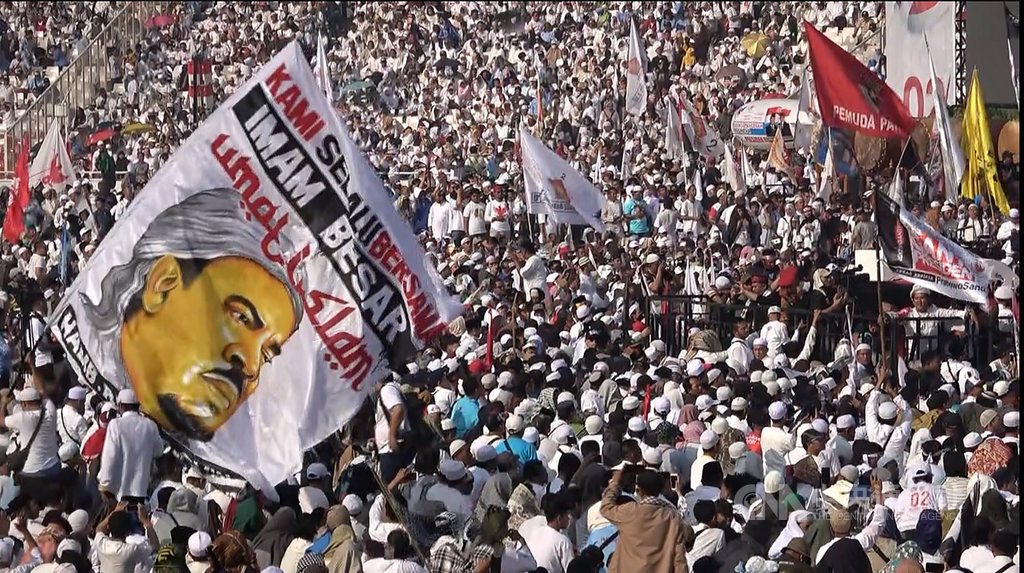 印尼反對陣營總統候選人普拉伯沃4月7日在雅加達國家體育館舉行造勢,民眾揮舞強硬派伊斯蘭團體「伊斯蘭防衛者陣線」領袖哈比比利奇的大旗。人在沙烏地阿拉伯的哈比比利奇透過錄影幫普拉伯沃拉票。中央社記者石秀娟雅加達攝 108年4月21日
