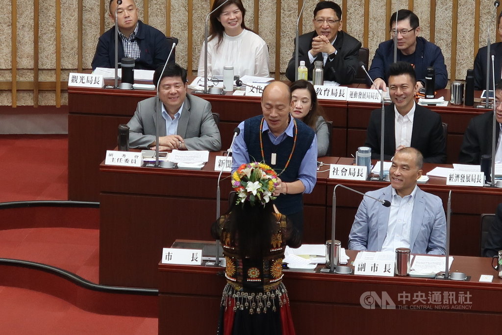 國民黨高雄市議員唐惠美(前)15日在市政總質詢時,送上一條琉璃珠項鍊給市長韓國瑜(2排左),還唱了一首「讀你」表達代表族人對他的相挺。中央社記者王淑芬攝 108年5月15日