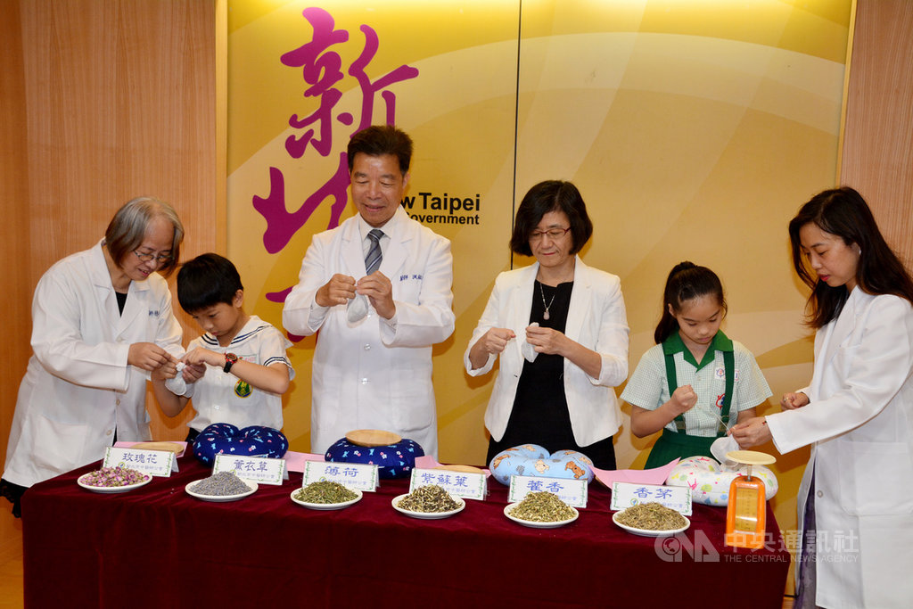新北市中醫師公會理事長洪啟超(左3)16日在記者會教導孩童製作香包,可以醒腦通竅不躁動。中央社記者黃旭昇新北攝 108年5月16日