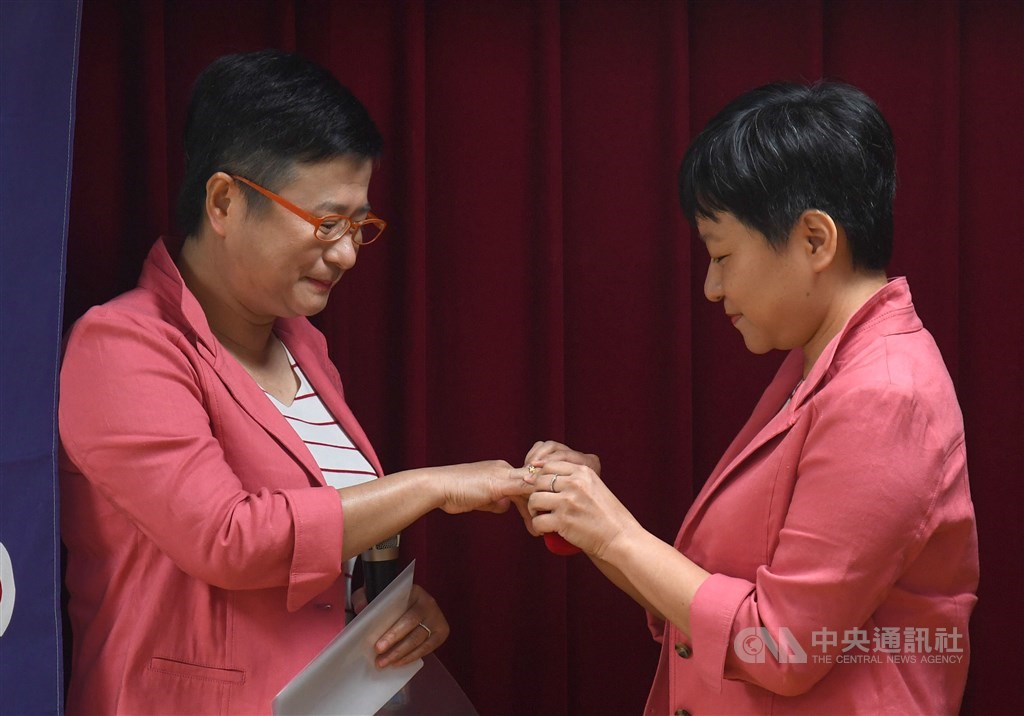 同志伴侶同時也是伴侶盟創辦人許秀雯律師(左)、秘書長簡至潔(右),24日到台北市中正戶政事務所辦理結婚登記,簡至潔為許秀雯戴上祖母留下的戒指。中央社記者王飛華攝 108年5月24日