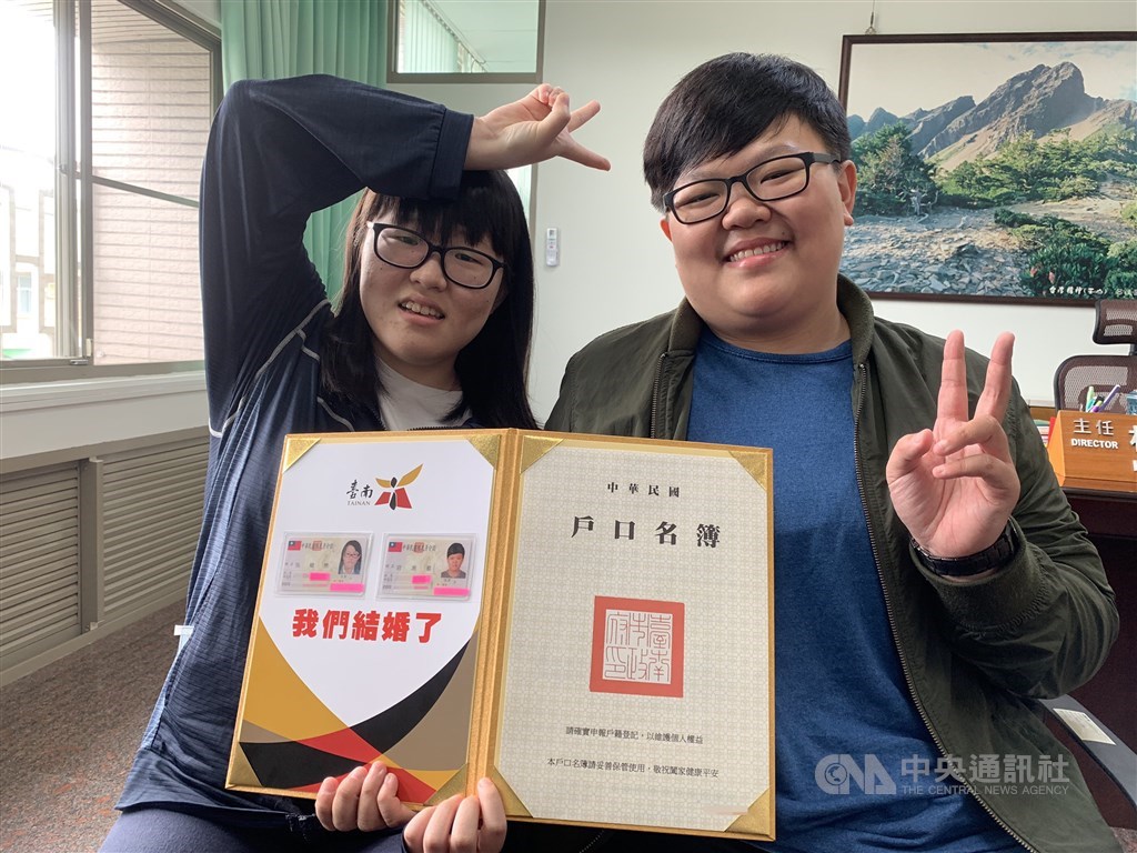 同婚登記24日上路,同性伴侶吳暐樂(左)、岩湘蓁(右)成了台南第一對完成登記的佳偶,看到身分證配偶欄有著對方的名字,兩人高興地比起「YA」的勝利手勢。中央社記者張榮祥台南攝 108年5月24日
