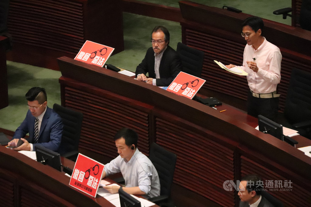 圖為修訂草案在香港立法會進行一、二讀時,泛民議員舉標語反對。(中央社檔案照片)