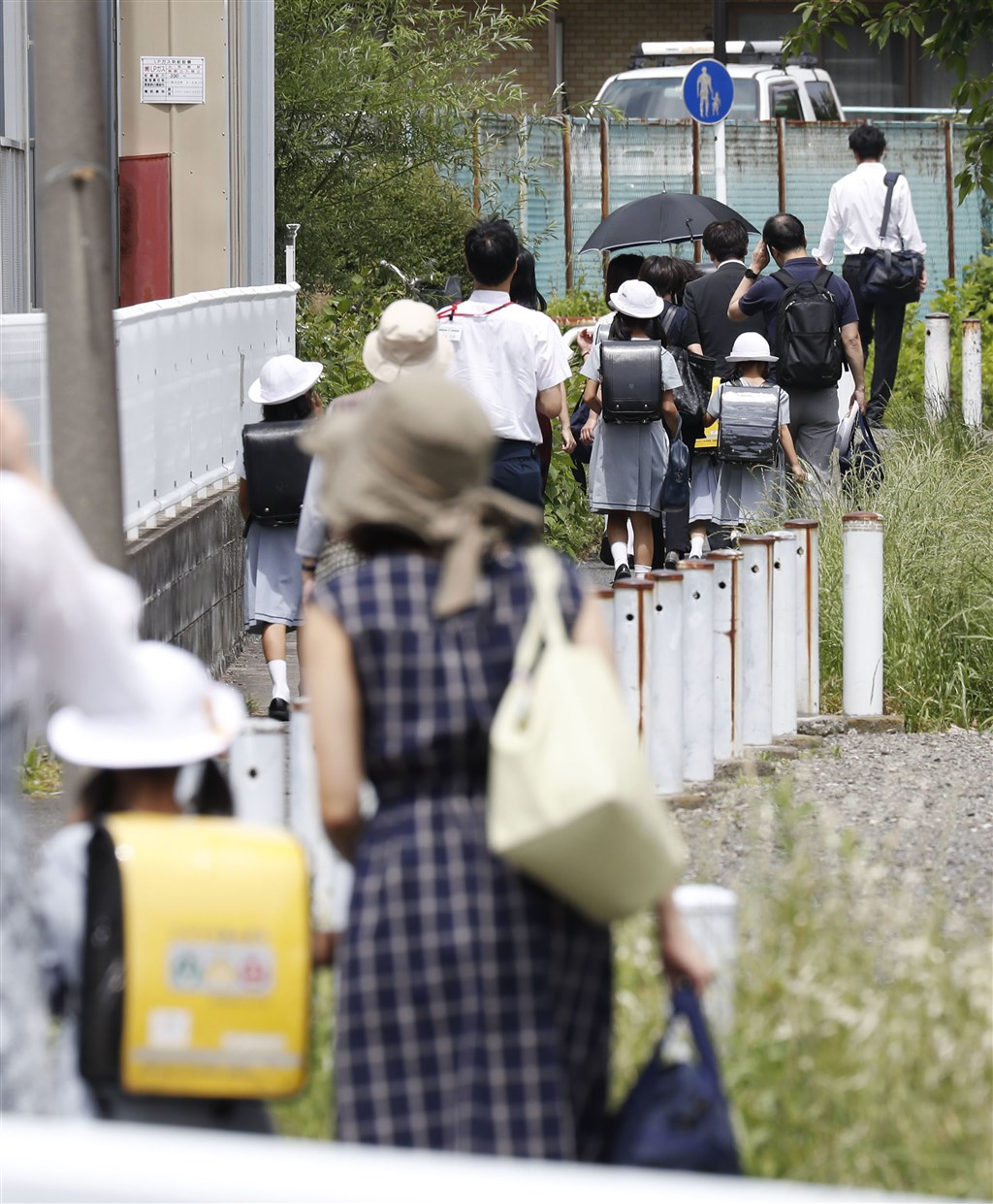 川崎市登戶CARITAS小學校車停靠處28日發生砍人案,案發後家長陪同學生放學回家。(共同社提供)