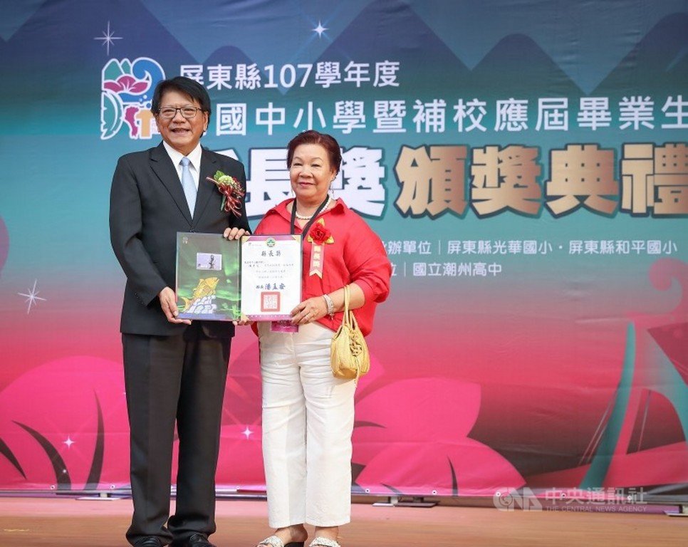 屏東縣政府2日舉辦高國中小暨補校應屆畢業生縣長獎頒獎典禮,70歲阿嬤陳秀花(右)每天清晨到魚市場做生意,晚上到補校念書,從國小到國中10年不間斷,獲縣長潘孟安(左)頒獎表揚。(屏東縣政府提供)中央社記者郭芷瑄傳真 108年6月2日