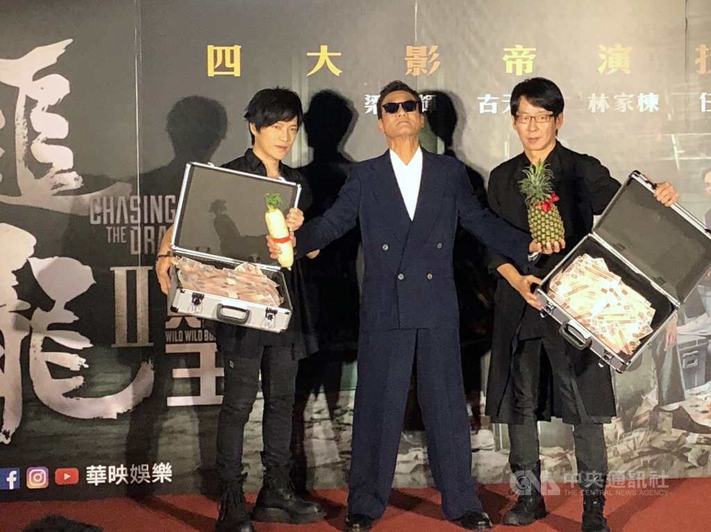 港星梁家輝(中)10日晚間在台北出席新片「追龍II:賊王」首映會,樂團五月天成員怪獸(左)、冠佑(右)到場支持,送上白蘿蔔和鳳梨,祝福票房買氣旺,開出好彩頭。中央社記者洪健倫攝 108年6月10日