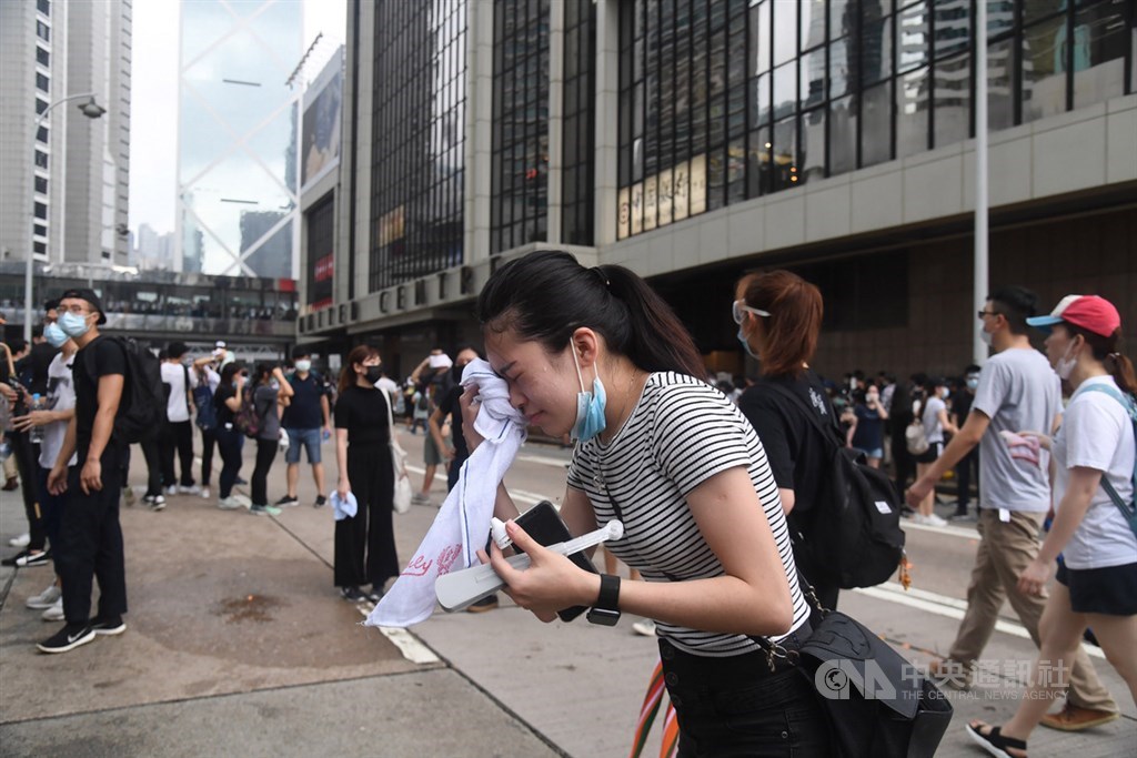 香港警方12日下午對集結抗議反送中的民眾作法轉趨強硬,近4時左右施放催淚彈,有民眾經不住催淚彈刺激,趕緊拿出毛巾擦臉。中央社記者王飛華攝 108年6月12日