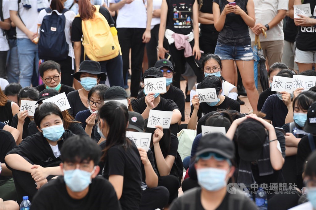 香港反送中抗議潮延燒,繼9日大遊行後,12日又有大批年輕人包圍立法會及占領主要幹道,部分抗議民眾在場席地而坐,手持「撤回」兩字標語表達訴求。中央社記者王飛華攝 108年6月12日