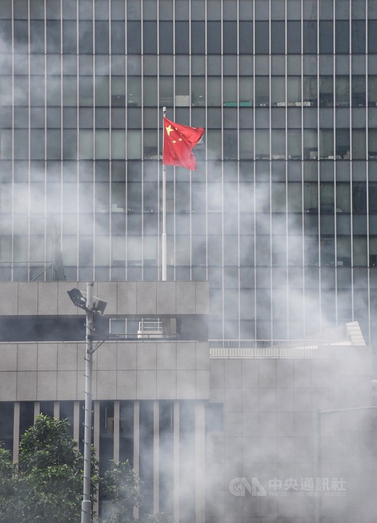 香港警方12日下午陸續向聚集在立法會外周邊區域的反送中民眾發射催淚彈,一旁五星旗靜靜在催淚彈煙霧中飄揚。中央社記者王飛華攝 108年6月12日