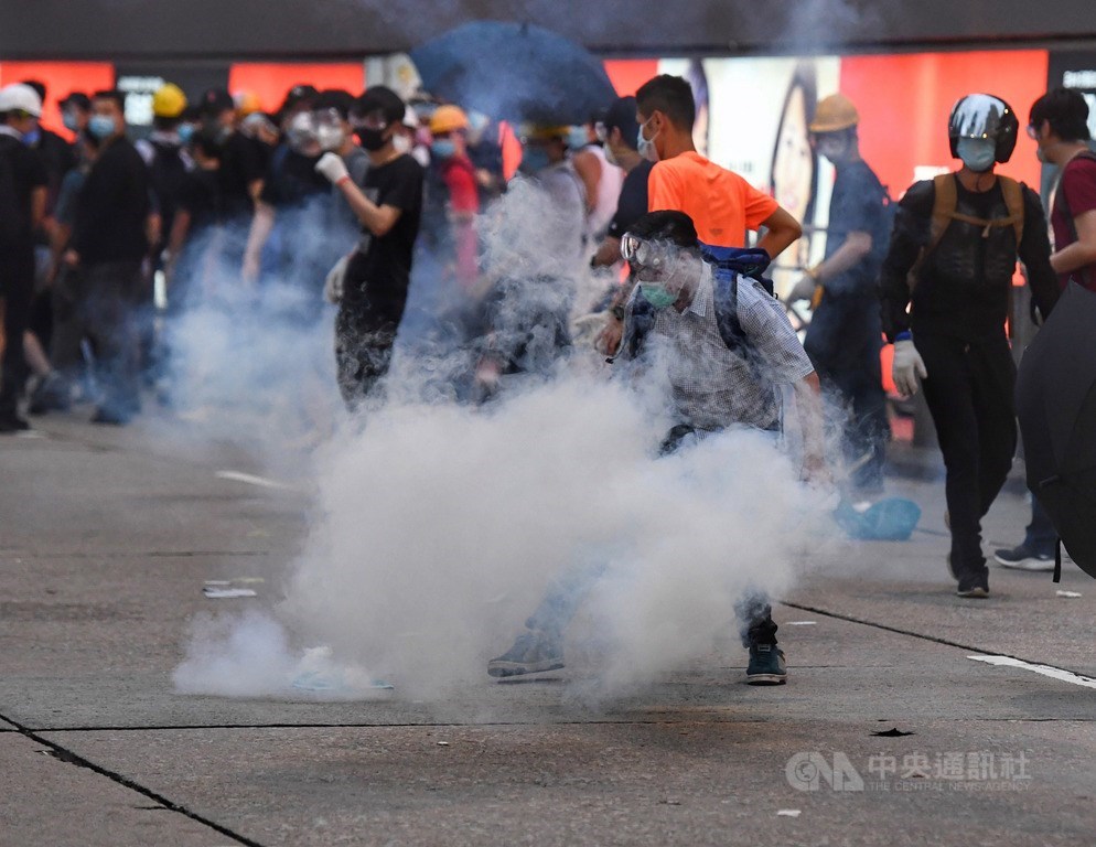 香港警方12日下午針對立法會外反送中抗議群眾發射催淚彈意圖驅離,有抗議人士試圖撿起催淚彈丟回給警方。中央社記者王飛華攝 108年6月12日