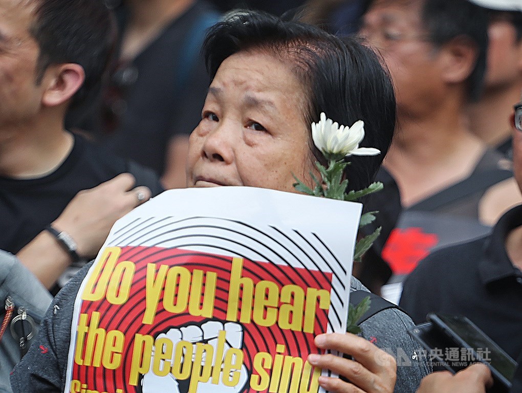 香港民眾16日參與反修訂逃犯條例大遊行,民眾手持白花,悼念墜樓身亡的反送中男子。中央社記者裴禛香港攝 108年6月16日