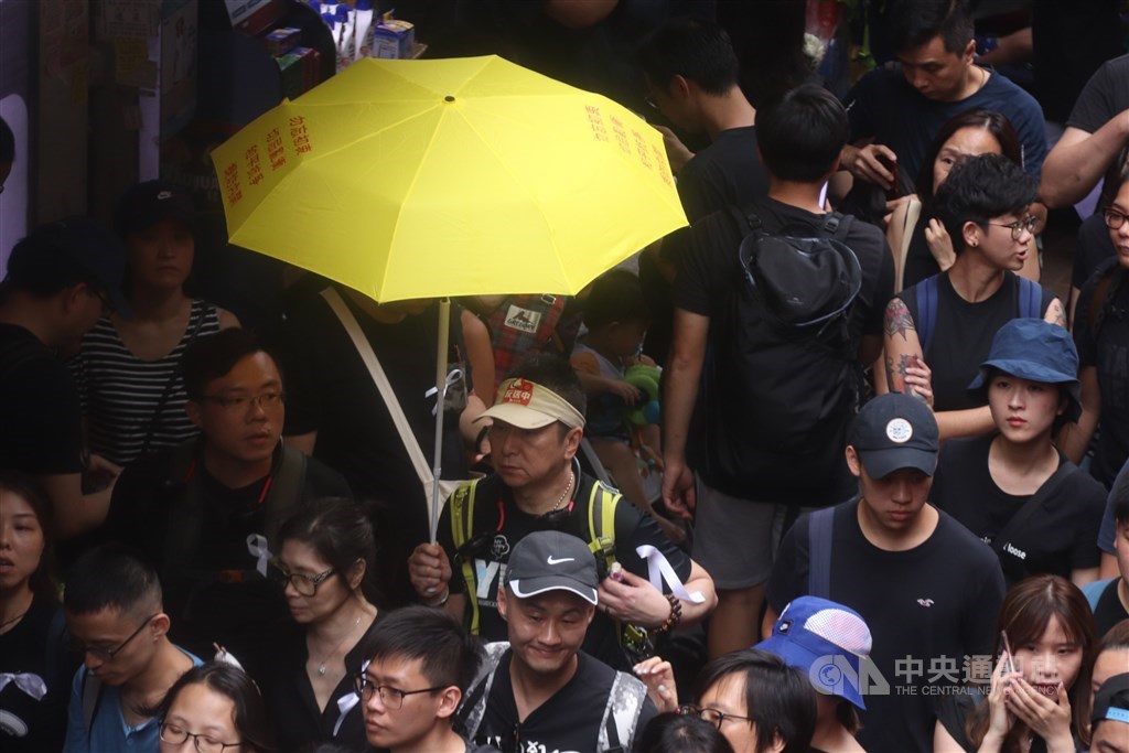 香港16日的反送中遊行隊伍中,有人手持代表占中運動的黃雨傘。 中央社記者張謙香港攝 108年6月16日