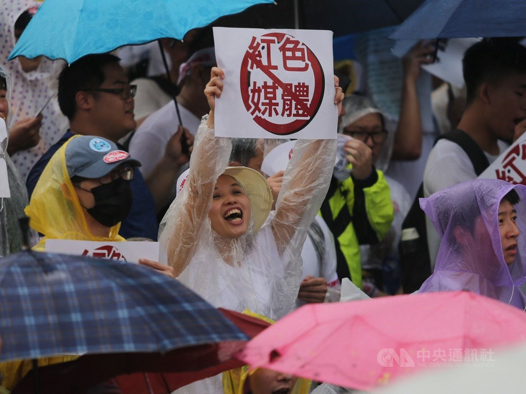 「拒絕紅色媒體、守護台灣民主」活動23日下午在凱達格蘭大道登場,許多民眾穿雨衣、撐傘到場參與,有人舉出反紅色媒體標語。中央社記者徐肇昌攝 108年6月23日