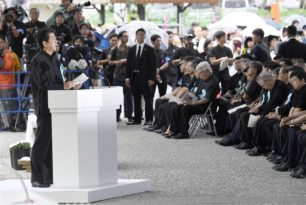 日本沖繩縣23日追悼沖繩戰役陣亡者,首相安倍晉三(前左)出席致詞,遭台下民眾嗆「滾回去」。(共同社提供)