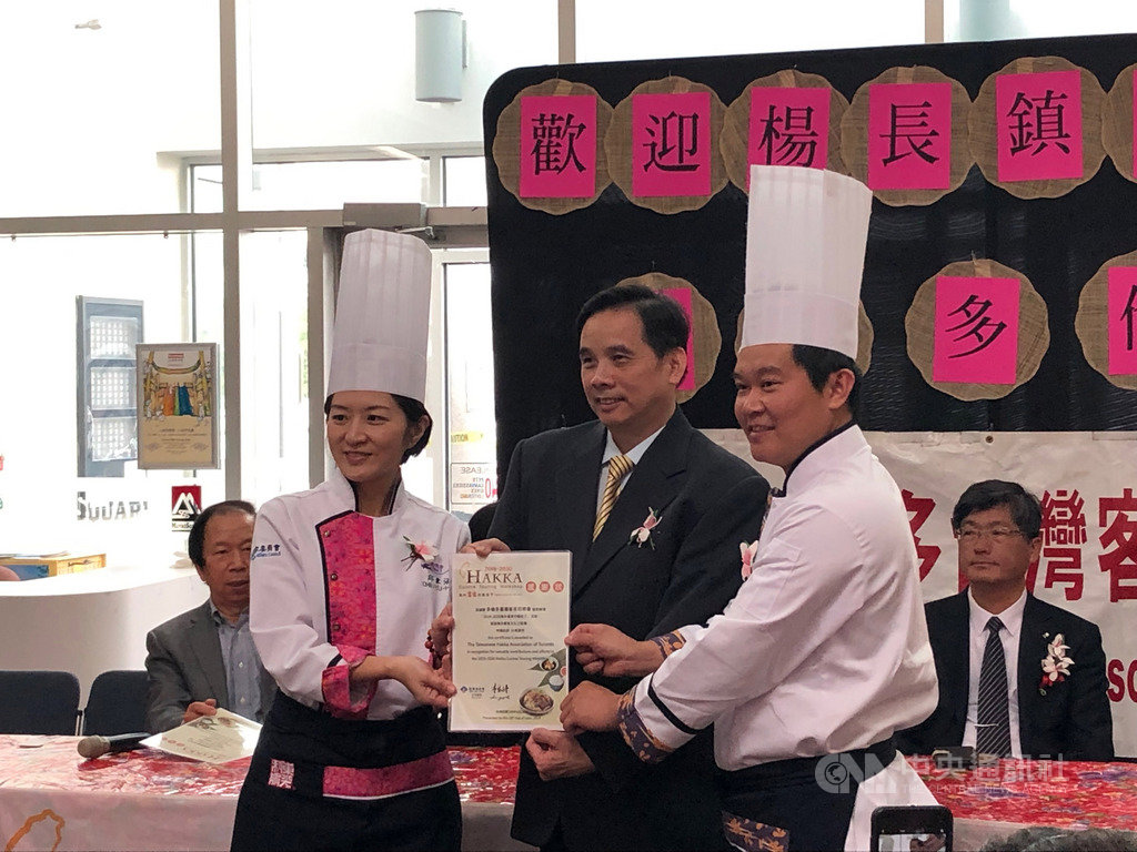 邱聿涵(左1)和溫國智(右1)兩位以客家文化美食為專長的知名大廚,在多倫多現場示範經典客家料理烹調秘技。主辦方多倫多台灣客家同鄉會會長邱文濱(中)致感謝狀。中央社記者胡玉立多倫多攝 108年6月29日