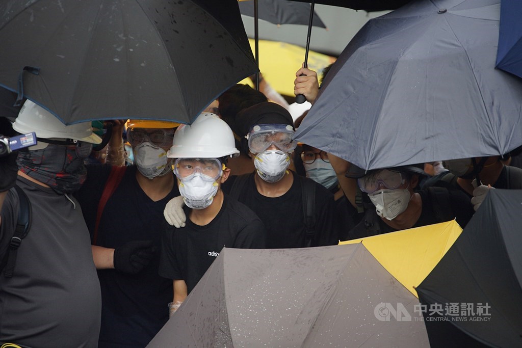 香港主權移交22週年,官方預定1日早上8時舉行升旗典禮,一群反對港府修訂逃犯條例的示威者試圖阻止升旗儀式進行,示威者穿戴防護裝備,以雨傘阻擋警方噴灑辣椒水。中央社記者裴禛香港攝 108年7月1日
