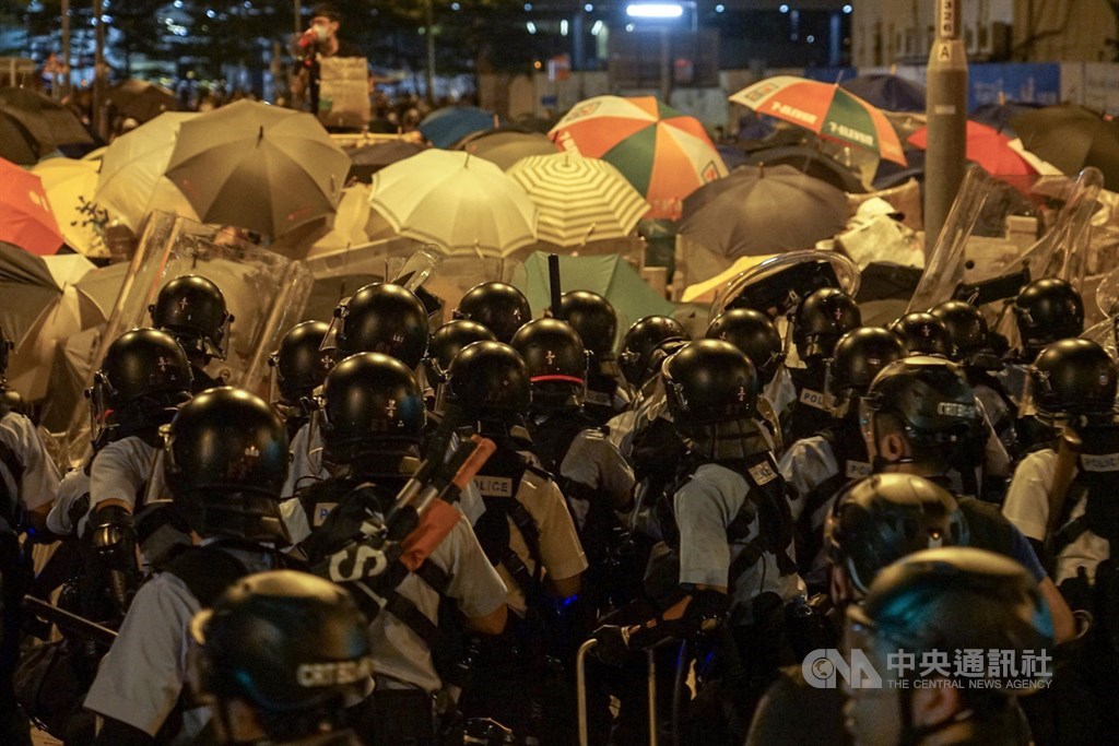 大批香港示威民眾1日晚間闖入立法會並占據議場,香港警方出動強勢警力待命驅離,2日凌晨正式行動,發射催淚瓦斯等,示威者高舉手中雨傘,全力阻擋。中央社記者裴禛香港攝 108年7月2日