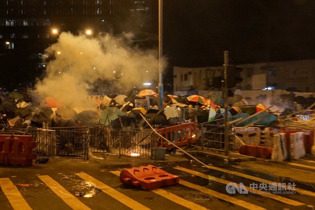數百名手持防暴器械的香港警察2日凌晨採取行動,開始以鎮暴隊形驅離在場的示威者,有示威者向警察扔擲磚塊,警方則向示威者發射催淚瓦斯,現場陷入混亂,群眾紛紛舉起雨傘阻擋。中央社記者裴禛香港攝 108年7月2日