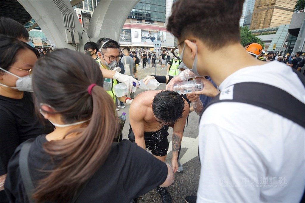 反逃犯條例示威者在香港主權移交22週年當天上午擋住馬路,試圖阻止七一升旗典禮,與警方發生衝突。圖為群眾為被員警胡椒噴劑噴灑到的示威者沖洗身體。(中央社檔案照片)