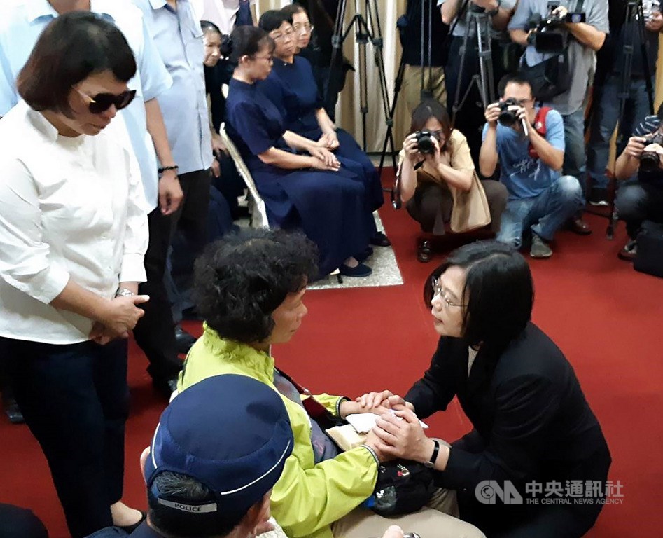 總統蔡英文(前右黑衣者)4日下午親自前往嘉義市立殯儀館,慰問因公殉職的鐵路警察李承翰家屬,蹲下身來緊握李承翰母親的手。中央社記者黃國芳攝 108年7月4日