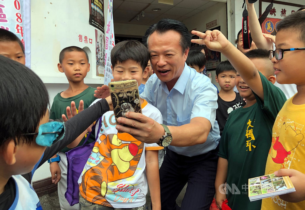 嘉義縣約有6、7成民眾出外就業,縣府18日特別啟動學童社區踏查活動,嘉義縣長翁章梁(中)參與啟動儀式後,與學童自拍留念。中央社記者黃國芳攝 108年7月18日
