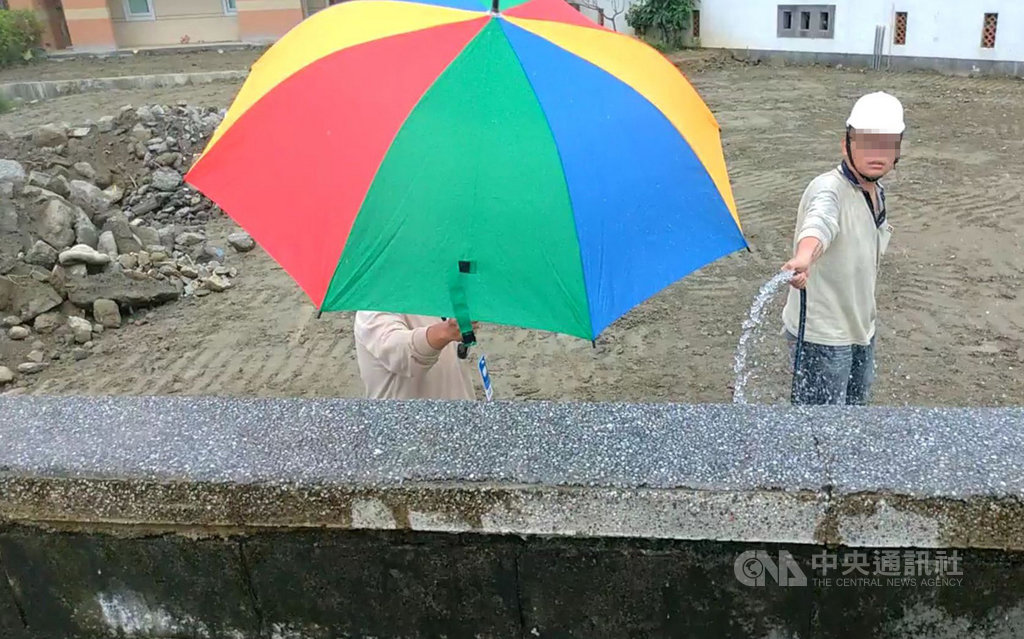 高雄市長韓國瑜妻子李佳芬在雲林縣古坑鄉農舍涉違建風波,古坑鄉公所19日丈量主建物後,經比對使用執照竣工圖,與現況確有差異。到場採訪的媒體記者遭現場工人以沖洗牆壁為由噴水,並拿雨傘遮臉。(民眾提供)中央社記者葉子綱傳真 108年7月19日